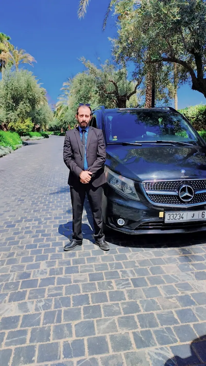 A Damask driver in a suit beside the Mercedes-Benz Vito